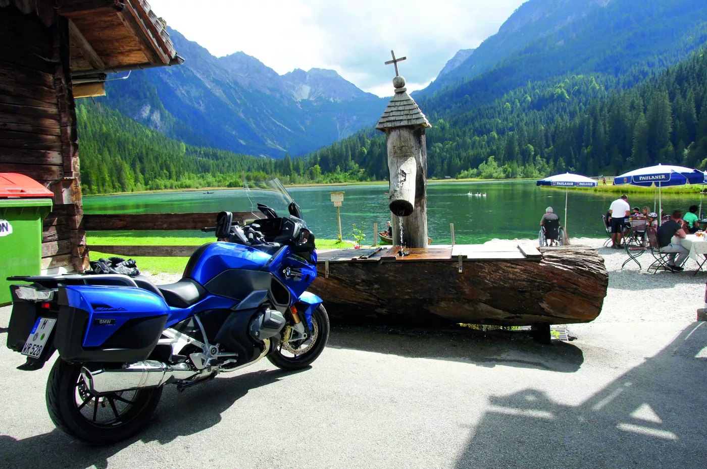 Motorräder an einem Bergsee mit Wegkreuz und Rastbank